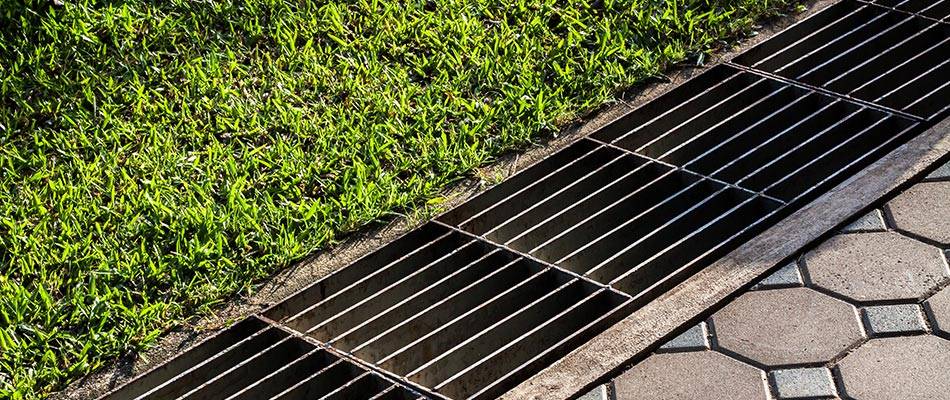 Catch basin drain system installed alongside a lawn and patio to manage water drainage effectively.