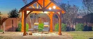 Custom outdoor living space with a pergola, ambient lighting, lounge chairs, and a stone patio designed for relaxation.